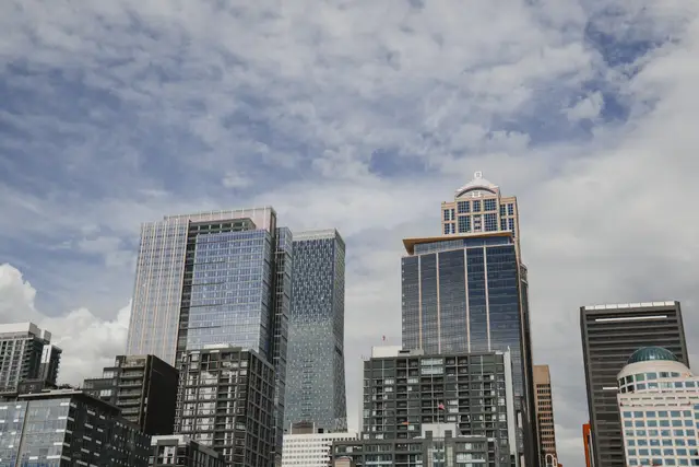 Several separate office towers of different heights and façades, seen together against a clouded sky.