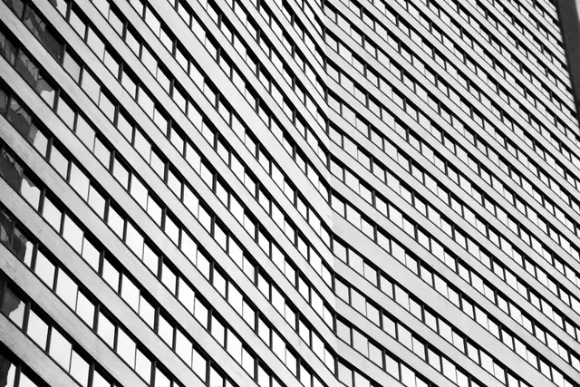 A commercial tower facade in oblique light, its window bands repeating floor after floor.
